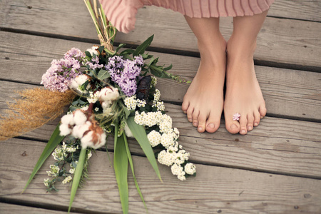 美丽的温柔的女孩，穿着一件桃色的连衣裙，走在乡村的木桥上，手里拿着一束花。