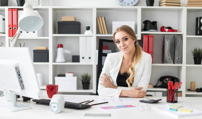一个年轻的女孩坐在办公室的电脑桌旁