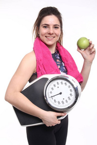 年轻女运动员拿着体重秤吃苹果