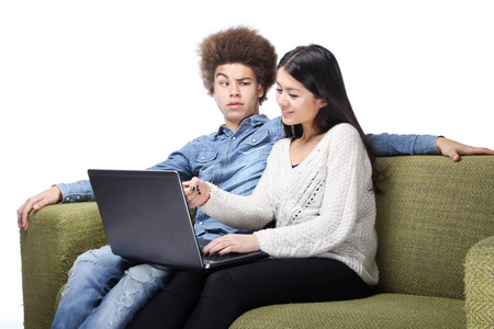 一对漂亮的幸福夫妇坐在沙发上，用笔记本电脑