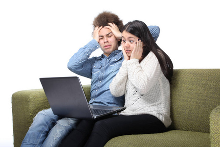 一对漂亮的幸福夫妇坐在沙发上，用笔记本电脑