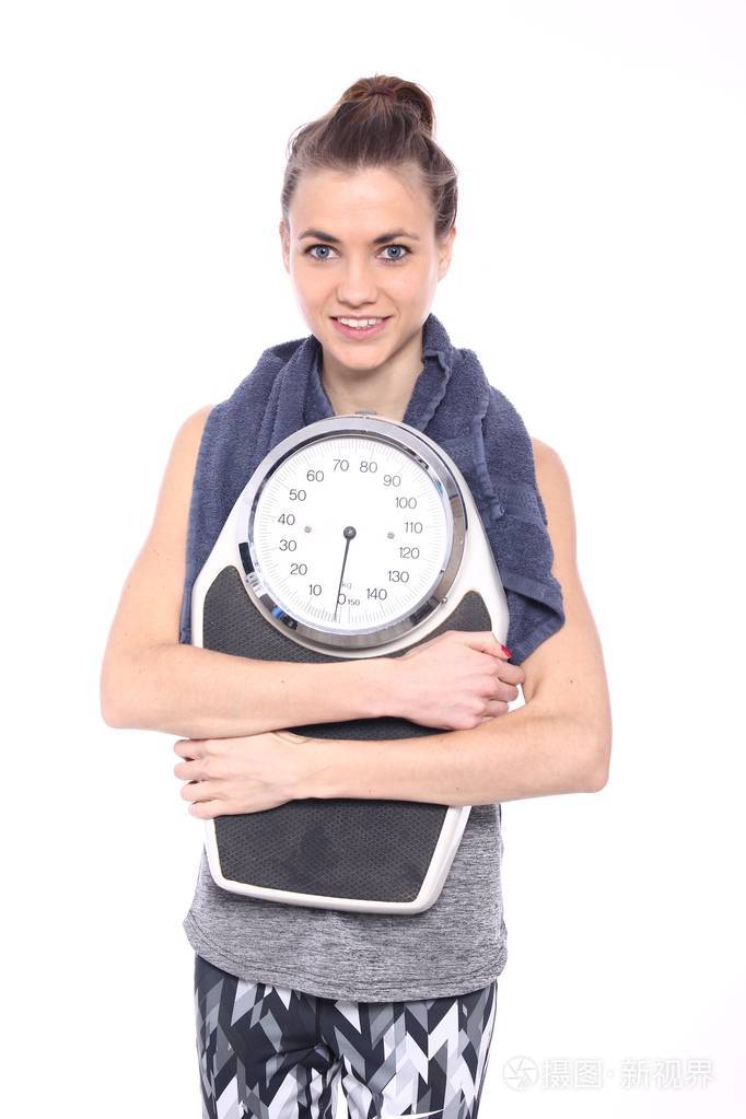 年轻的女运动员拿着体重秤