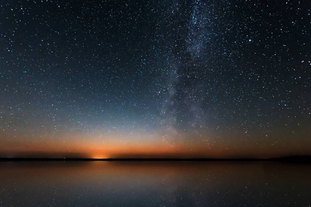 在湖的星星蓝夜星空,银河系在湖泊和俄罗斯村庄上方.