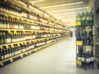 模糊的抽象葡萄酒通道与价格标签在德克萨斯州美国杂货店。 在超市货架上放散了一排排红白葡萄酒酒瓶。 酒精饮料概念背景