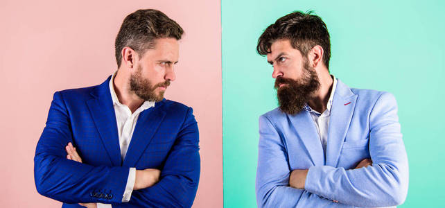 商业伙伴的竞争者在西装与紧张的胡子面孔。商人时尚外表夹克粉红色蓝色背景。紧张的表情竞争者。商业竞争与对抗