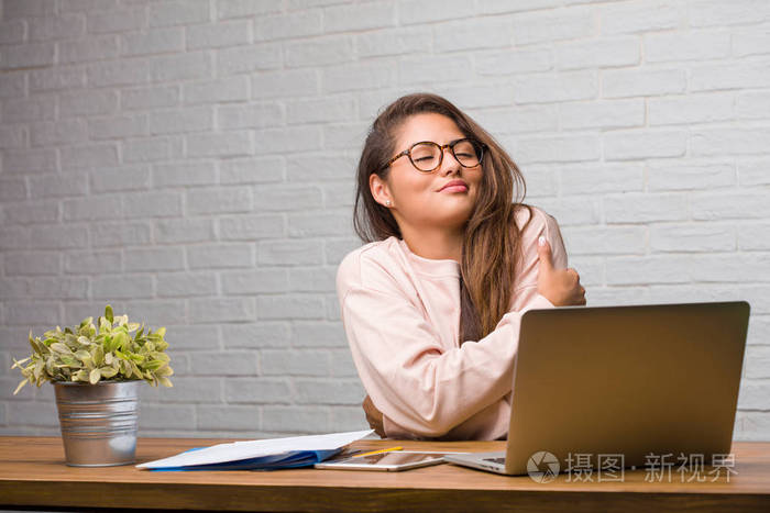 年轻学生拉丁女子坐在桌子上的肖像,骄傲和自信