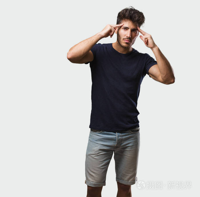 年轻的帅哥站着,做着专注的手势,直视前方,专注于一个目标