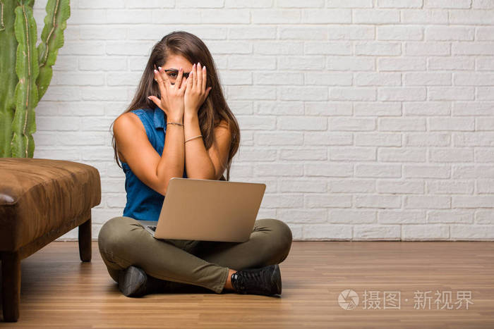 坐在地板上的年轻拉丁女人的肖像感到担心和害怕