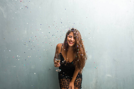 年轻的拉丁女人庆祝新年或活动。 兴奋而快乐地拿着香槟瓶和杯子。