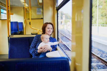 带着小女孩在火车上看窗户的女人。 母亲带着婴儿乘坐铁路公共交通工具。 带孩子旅行