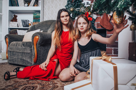 两个女孩的姐妹带着礼物盒，在装饰圣诞节和新年的房间里放松和有趣的圣诞树
