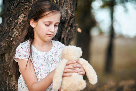4.带着玩具熊的小女孩正在森林里欣赏日落时美丽的秋景