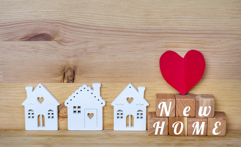 新的家庭概念，白色的小房子和红色的心在木制的背景上