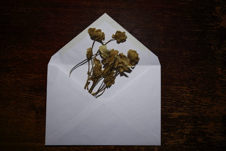 信封上有一束干燥的夏季花在木桌背景上。