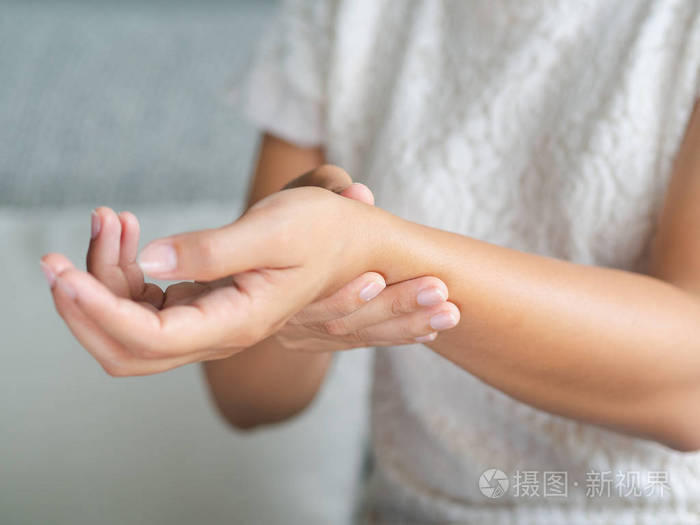 坐在沙发上的特写年轻女子握住她的手腕. 手受伤感觉疼痛.