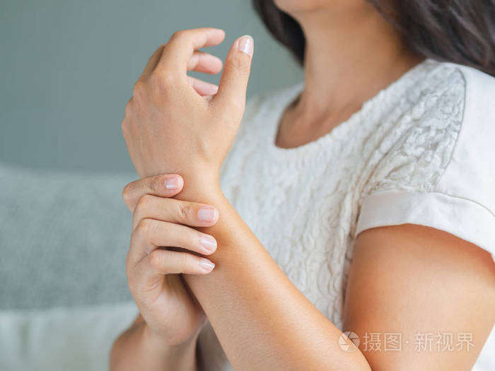 坐在沙发上的特写年轻女子握住她的手腕 手受伤感觉疼痛.