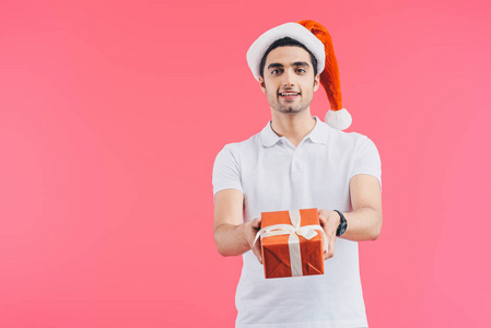 带着圣诞帽的微笑帅哥送礼物盒隔离粉色新年概念