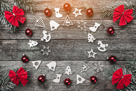冷杉树枝上有红色的蝴蝶结和圣诞手工玩具和球，在木制的灰色背景上创造了一个圆圈，为圣诞贺卡提供文字空间。 光的影响