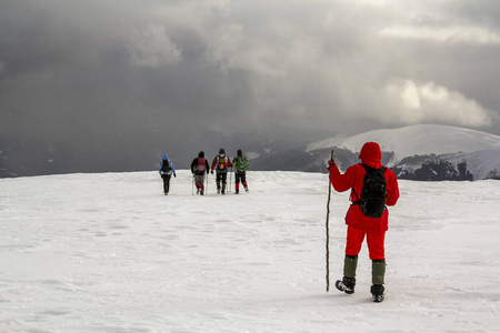冬天的游客徒步旅行者白雪覆盖了群山和天空中戏剧性的云彩