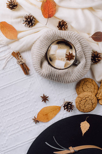 秋冬作文。 热咖啡与棉花糖围巾，饼干，帽子，凸起和秋天的叶子。 平躺式顶部视图