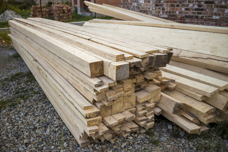 建筑工地上一堆天然棕色不均匀粗糙的木板。 木工建筑修理用工业木材和屋顶建筑用家具木材材料。