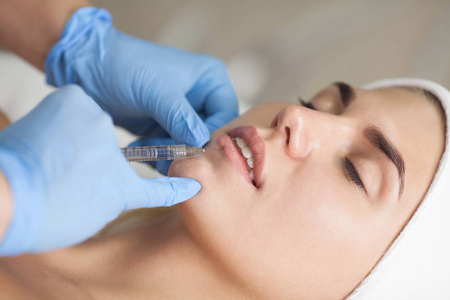 美容师在病人的嘴唇上注射肉毒毒素。 美容护肤。