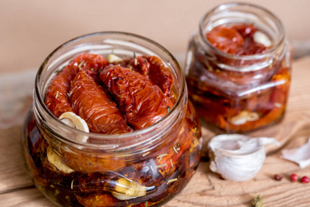 晒干的西红柿与百里香和海盐在橄榄油在一个玻璃罐子上的旧木制背景。红胡椒和大蒜。