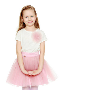 美丽的金发小女孩,留着长发,穿着一条郁郁葱葱的短粉红色裙子和白色