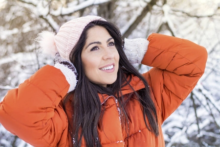 美丽的微笑的年轻女子在冬天的雪林里。冬天的假期