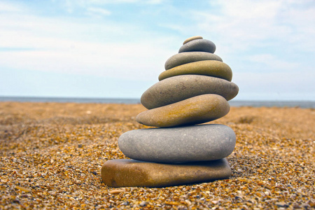 沙子上的石头金字塔象征着禅宗的和谐平衡。 背景中的海洋