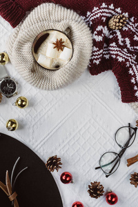 冬季概念。 平躺视图的颠簸和格子纹理红色毛衣在白色背景与一杯咖啡眼镜和一顶帽子。