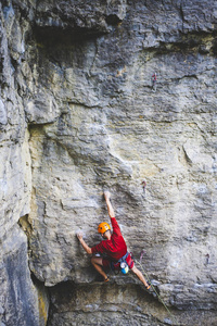 一个戴头盔的人爬上岩石。 在大自然中攀爬。 户外健身。 积极的生活方式。 极限运动。 运动员在自然的解脱中训练。 乌克兰的攀岩。