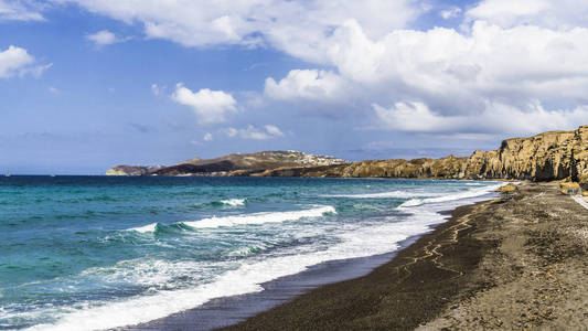 地中海的海浪在桑托里尼岛上一个荒无人烟的海滩的黑沙上描绘了令人惊叹的画面。