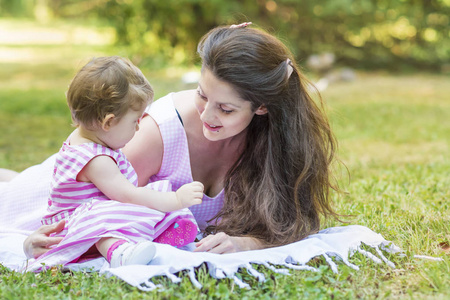 快乐的母亲和她的女婴在夏天的公园里。母亲和女儿。幸福的家庭母亲和孩子
