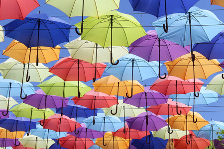 五颜六色的雨伞在蓝天上飞舞。 夏季