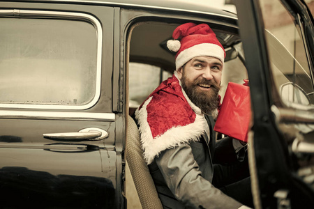 戴着红帽子的男子送圣诞礼物在复古汽车