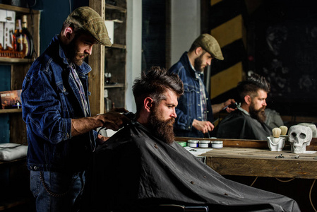 理发师发型的野蛮胡子客户端与剪刀。时髦的客户得到理发。理发师与理发剪工作的发型胡子男子理发店背景。时髦的生活方式概念