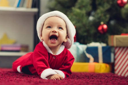 圣诞老人西装革履躺在圣诞树前的红地毯上的笑着的小的肖像和礼物