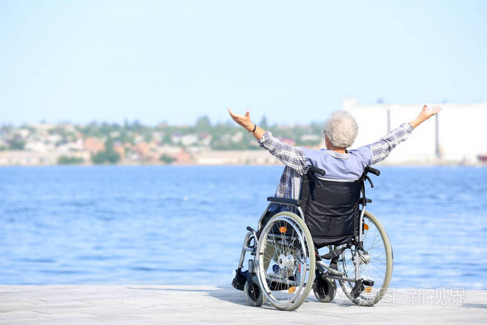 坐轮椅在河边的快乐老年妇女