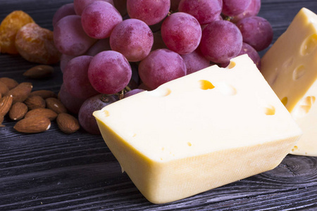 奶酪切割无花果坚果蜂蜜葡萄在黑暗的乡村木板背景。 顶部视图