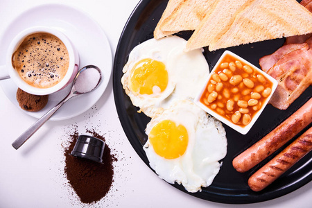 传统的英式丰盛早餐的顶部视图与煎蛋，香肠，豆类，培根，烤面包和橙汁分离在白色背景。