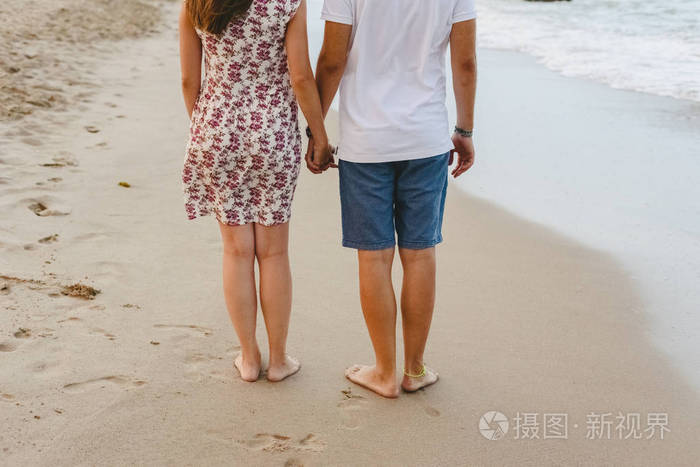 一对相爱的夫妇在秋天赤脚的海滩上散步