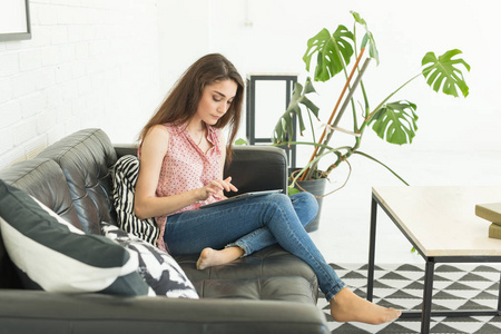人, 内部和休闲概念愉快的年轻妇女与平板电脑铺设在沙发上