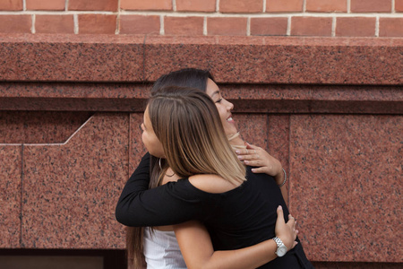 城市相遇两个朋友在街上拥抱的快乐相遇照片