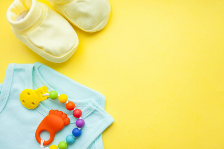 s shoes and toys on yellow background. Newborn. Top view