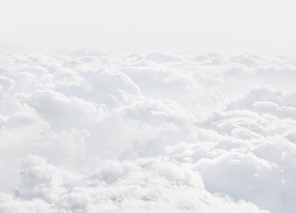 从云层上方的飞机上看到的天空。 抽象的自然背景与云的淡色调。 白色积云