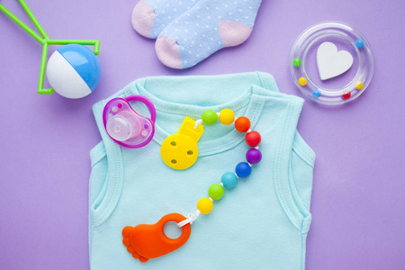 s shoes and toys on purple background. Newborn. Top view