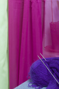 用钢编织针编织。 一团紫色的线和钢编织针在一个未完成的针织。