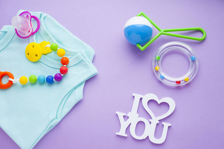 s shoes and toys on purple background. Newborn. Top view