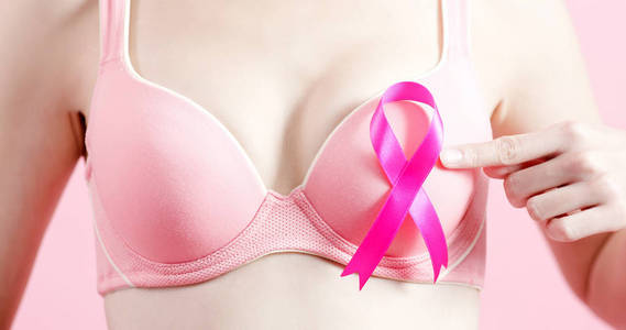 妇女展示粉红色丝带，预防乳腺癌的概念